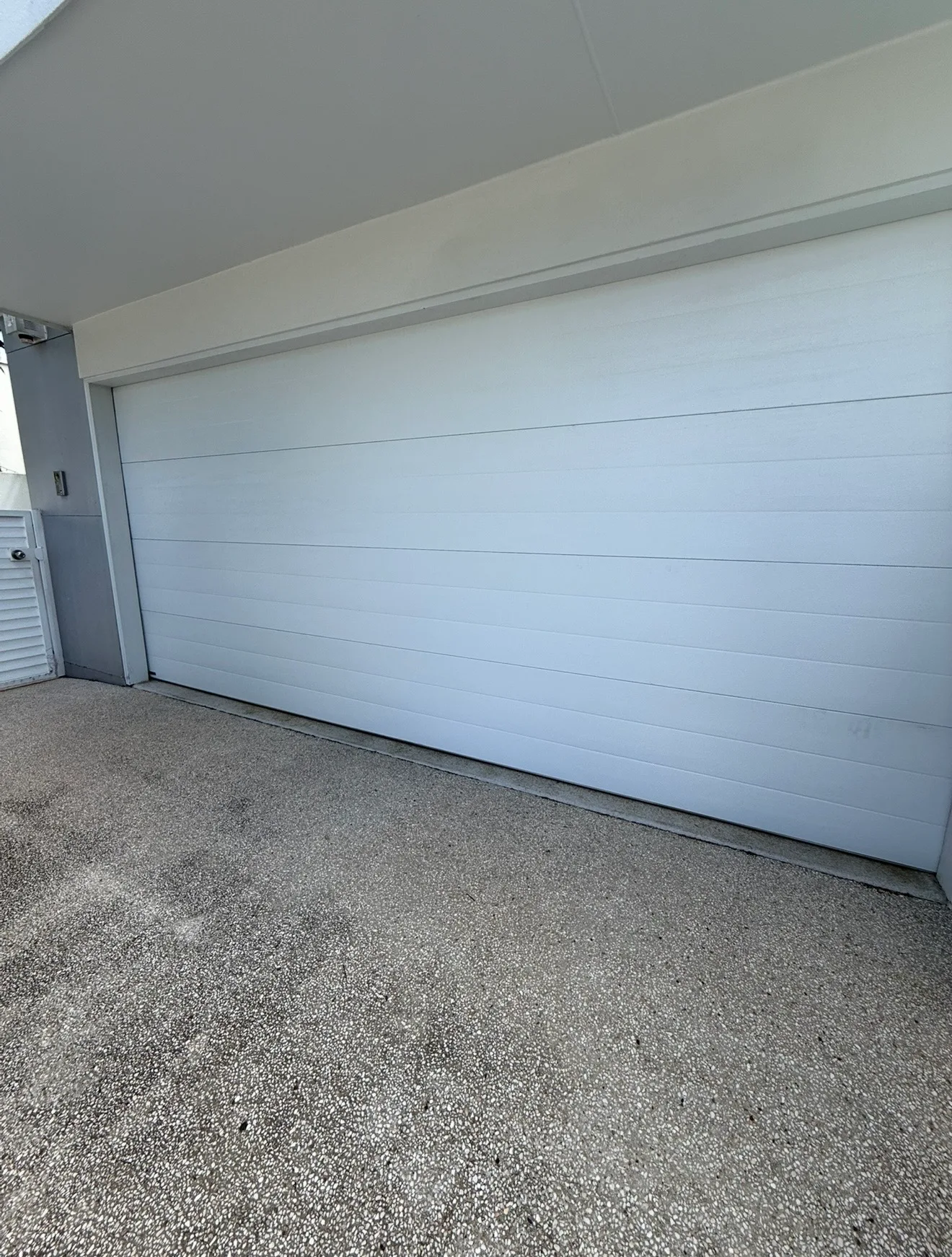 Garage door technician repairing a timber-look door outside a cottage near North Tamborine village